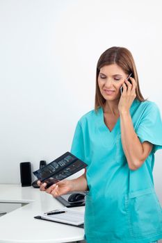 Portrait of a female dentist on call as she holds X-ray report in clinic