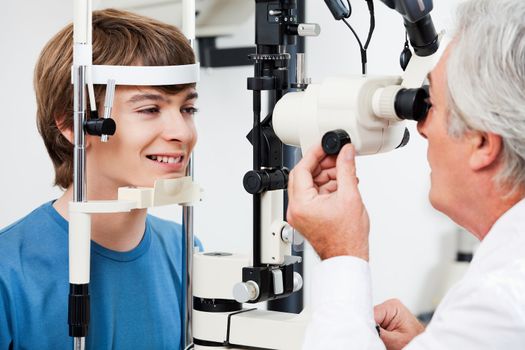 Smiling boy getting visual field test done by the optometrist