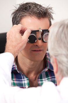 Optometrist using measuring spectacles on patient