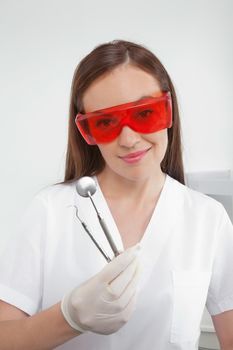 Portrait of dental nurse wearing eyewear while holding angled mirror and carver