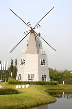 House with wind turbine sky background green grass.