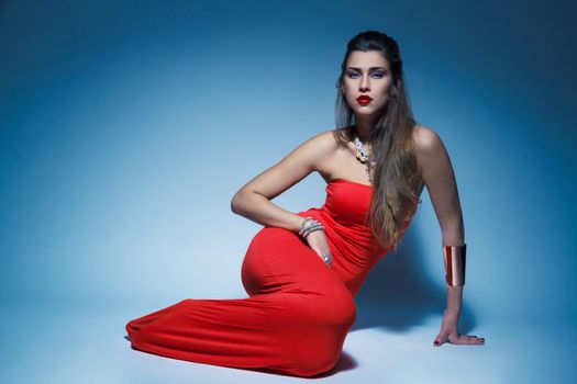 Young glamour woman in red dress long hair in studio
