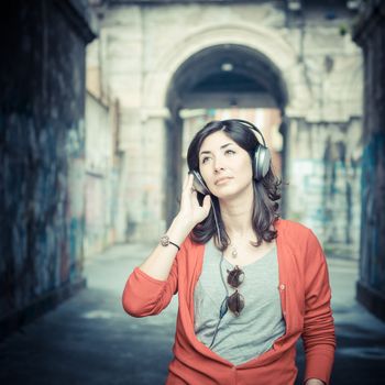 Beautiful stylish woman listening to music in the street 