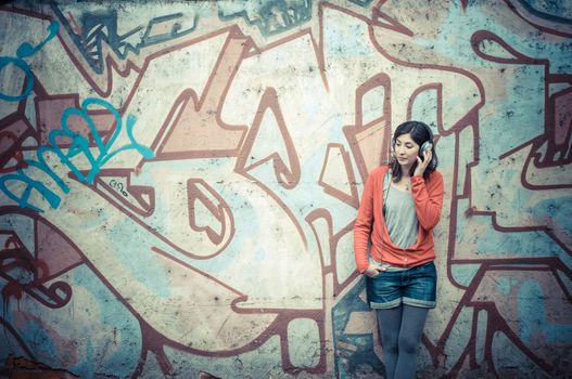 Beautiful stylish woman listening to music in the street 