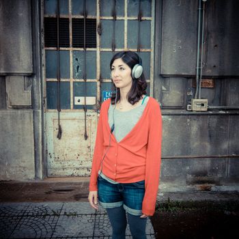 Beautiful stylish woman listening to music in the street 