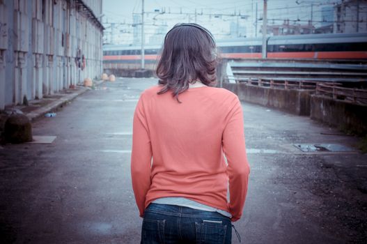 Beautiful stylish woman listening to music in railway
