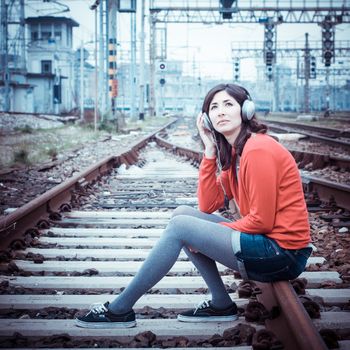Beautiful stylish woman listening to music in railway