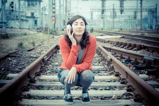 Beautiful stylish woman listening to music in railway