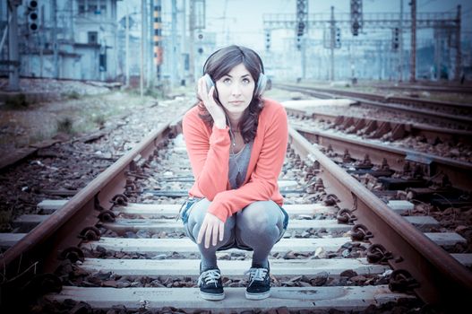 Beautiful stylish woman listening to music in railway
