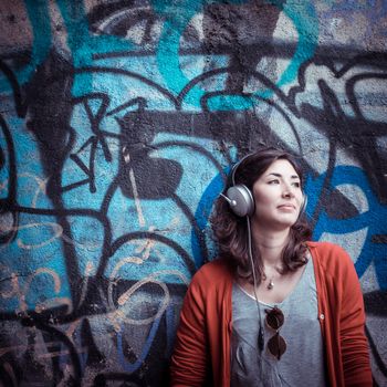 Beautiful stylish woman listening to music in the street 