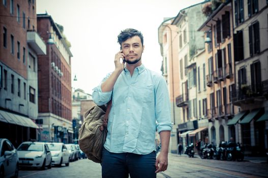 stylish man in the street at the phone in the city
