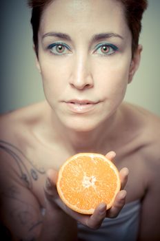 beautiful girl with short red hair and fruit on gray background