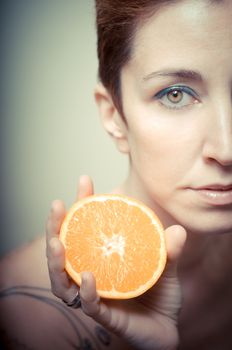 beautiful girl with short red hair and fruit on gray background