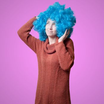 beautiful girl with curly blue wig and turtleneck on colorful background