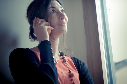 beautiful woman at home at the phone near window