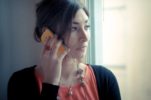 beautiful woman at home at the phone near window