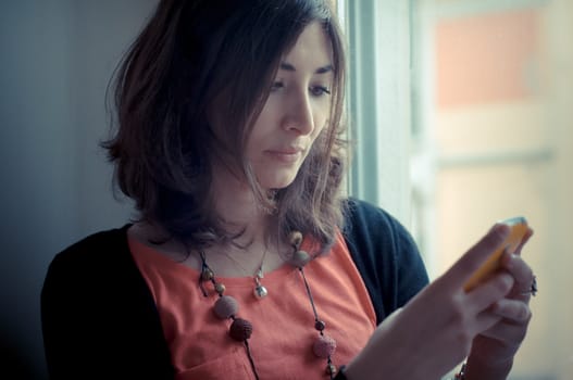 beautiful woman at home at the phone near window