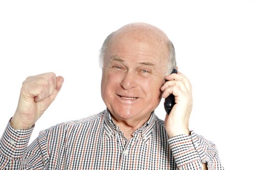 Happy senior man on his mobile phone rejoicing on hearing good news raising his fist in the air and smiling, isolated on white