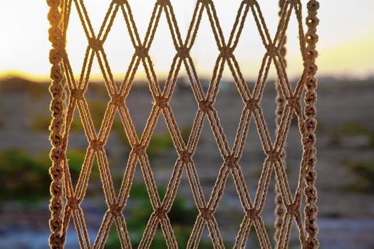 Texture of sunlight falling on a hammock style rope chair hanging from the ceiling on a balcony. Generic shot location hotel near Dwarka, Gujarat, India