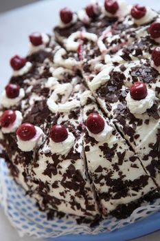 High angle closeup view of a delicious fresh blackforest gateau decorated with the traditional cream, chocolate flakes and cherries