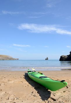 a green kayak with map on a beach ready for adventure on a sunny blue sky day