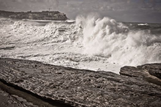 Huge white waves crashing ashore in a cyclone at Bondi Beach in Sydney, Australia