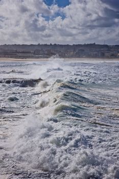 Rough turbulent seas along the coastline with cresting white waves during a cyclone on Bondi Beach in Sydney ,Australia