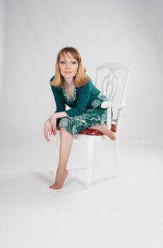 beautiful woman in a green dress sitting on a chair