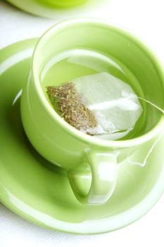 Tea bag in the green cup on a white background