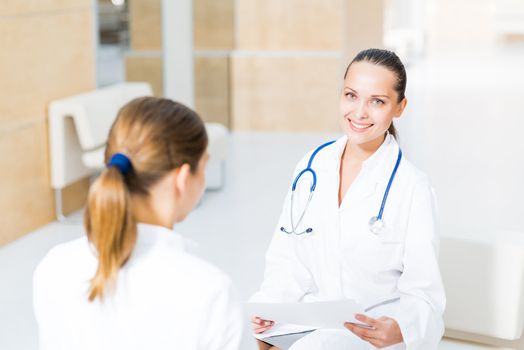 two doctors talking in the lobby of the hospital, sitting on the couch