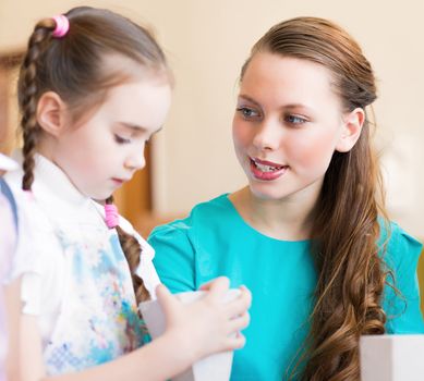 teacher talks to a schoolgirl, working at an art school