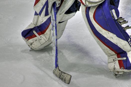 View of hockey goaltender pads and stick in defensive position