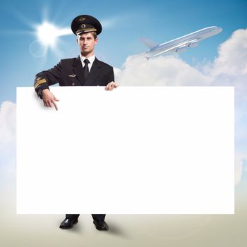 pilot in the form of holding an empty billboard on the background of sky and flying plane, place for text