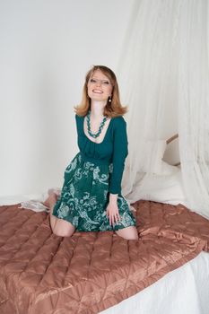 Sexy woman in green dress on the bed