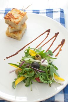 Healthy salad with cucumber and pepper on a plate with dressing and a potato omelette 