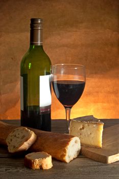 Glass of red wine with cheese and a sliced loaf of freshly made french bread