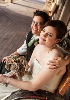 Smiling gay female couple sitting on rustic bench