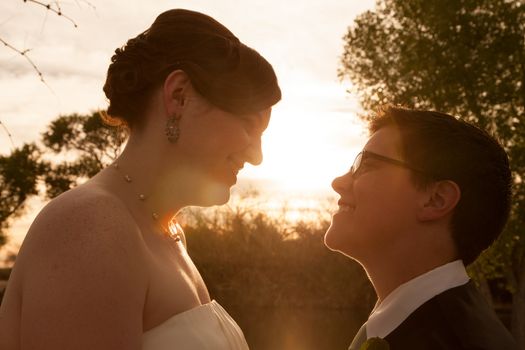 Same sex female bride and groom outdoors by sunset