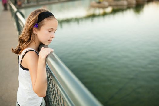 Girl standing on a bridge looking at water