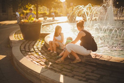 Family sitting by a fountain in downtown Montreal at sunset
