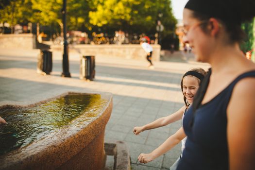 Mother and daughter laughing by a fountain in old Montreal