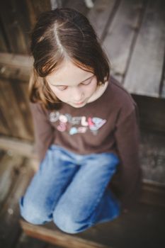 Sad little girl sitting on a patio