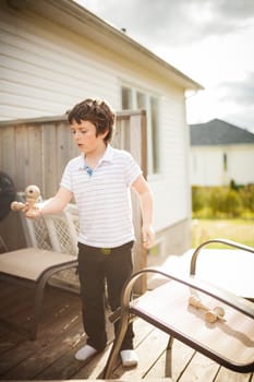 Boy playing cup and ball outside on a patio