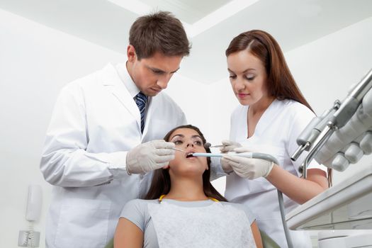 Young male dentist and nurse examining patient's teeth in clinic