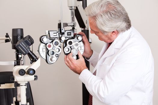 Doctor in ophthalmology clinic adjusting phoropter.