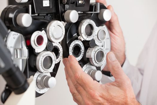 Optometrist changing settings in phoropter before an eye test