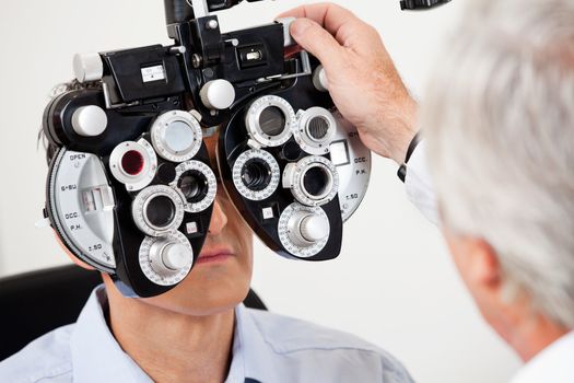 Optometrist performing eye test with phoropter on a male patient