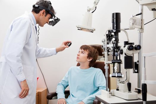 Young boy going through dilated retinal exam done by optometrist to detect eye disease