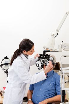 Female optometrist performing eye checkup with phoropter at clinic