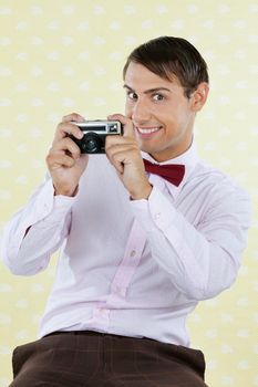 Portrait of male geek photographing through a retro camera over textured background